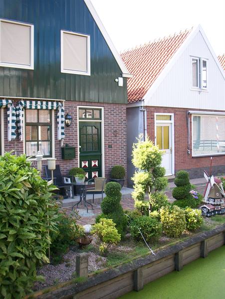 Brick and green wooden houses with striped awnings beside a canal