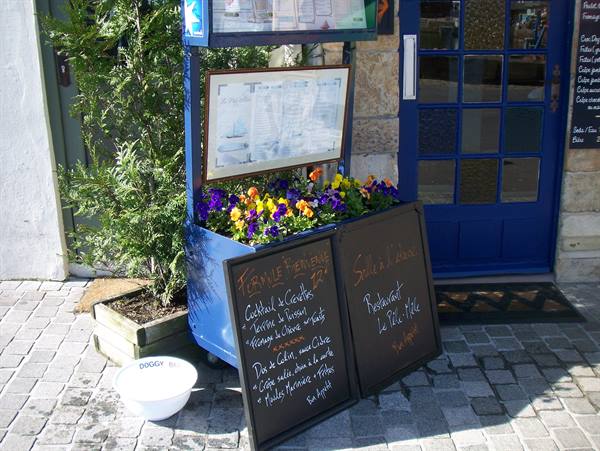 Chalkboard menus and flowers outside the blue door of Le Vieux Port restaurant