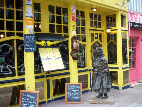Bronze statue in front of La Licorne's yellow half-timbered restaurant facade