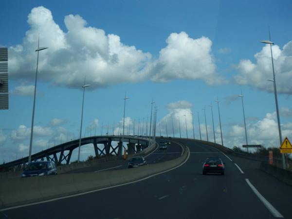 Cars climb the Saint-Nazaire bridge under white clouds and lampposts