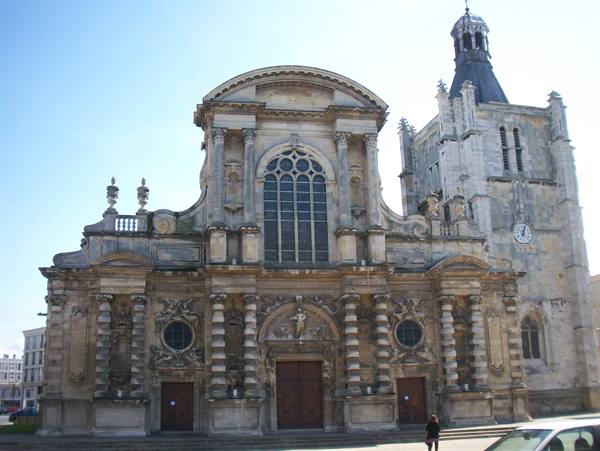Baroque stone facade of Le Havre cathedral, a tourist walks below