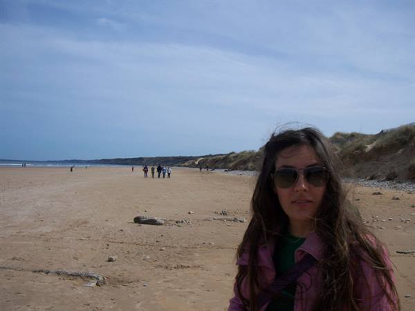 Girl with sunglasses and pink jacket on a windy sandy beach
