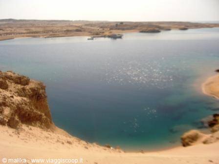Turquoise lagoon framed by sand dunes and desert rocky shores