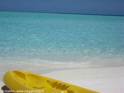 Yellow kayak on white sand in front of clear turquoise water