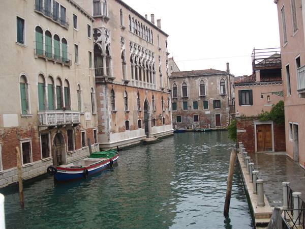 Venice canal lined with old palaces, a colorful boat moored