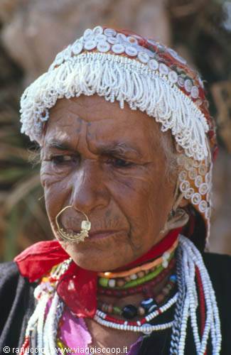 Elderly woman with golden nose ring, embroidered headdress and colorful bead necklaces