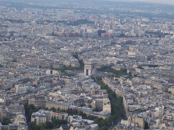 Arc de Triomphe in Paris seen from above among rooftops and tree-lined avenues