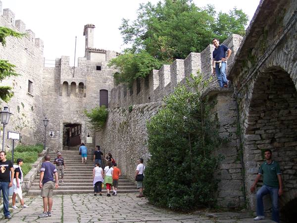 Tourists climb the stairs to Guaita fortress in San Marino, stone walls