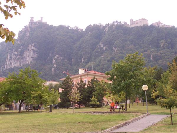 People picnicking in a green park beneath San Marino's towers