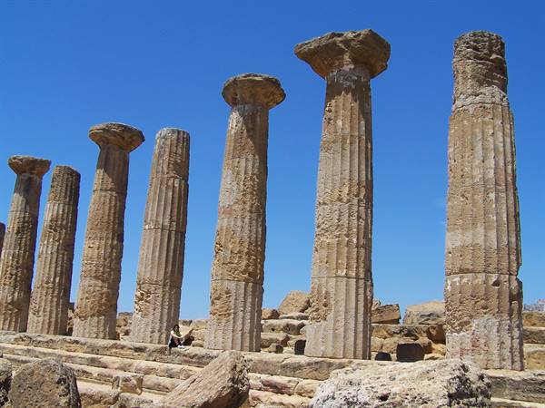 Doric stone columns at the Valley of the Temples, Agrigento, tourist sitting below