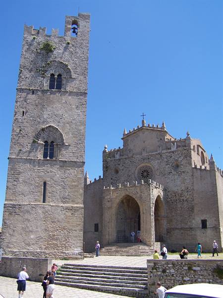 Tourists before Erice cathedral and stone bell tower under clear blue sky