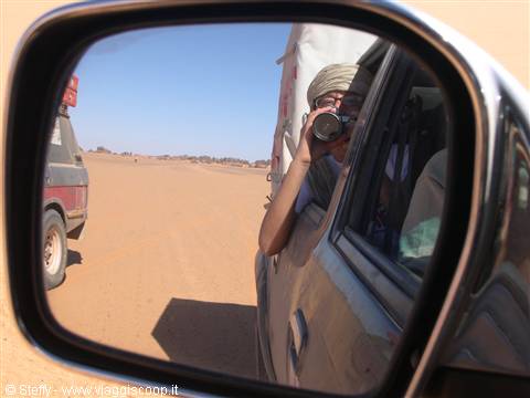 Turbaned tourist photographs himself in 4x4 side mirror, sandy desert