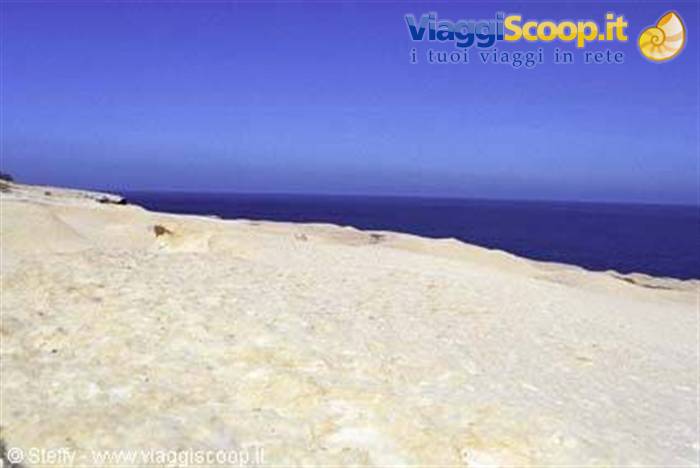 White limestone rocky cliffs overlooking deep blue sea under clear sky