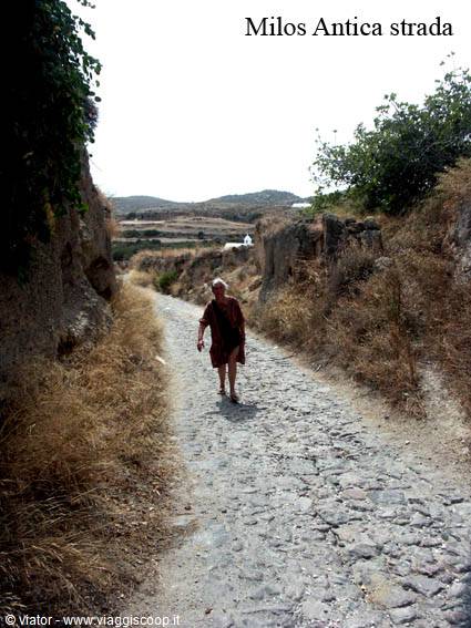Tourist walks along the old stone-paved road on Milos