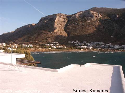 Whitewashed concrete terrace over Kamares bay, white houses beneath arid mountains