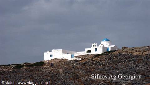 White church with blue dome on rocky hill in Sifnos