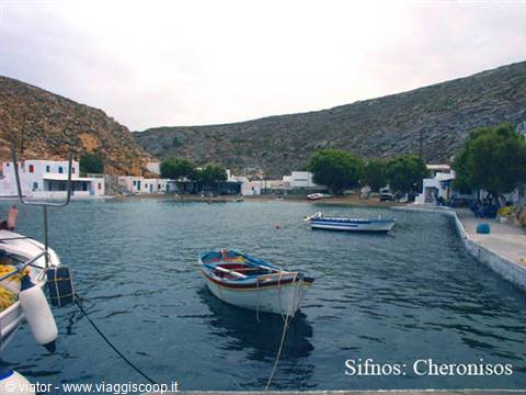 Fishing boats moored at Cheronissos harbor, Sifnos, among whitewashed houses and arid hills