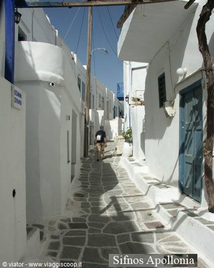 Paved alley in Apollonia, whitewashed houses, blue door, lone walker ahead