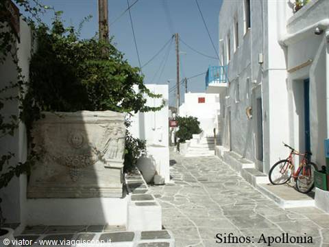 Paved alley in Apollonia, Sifnos: whitewashed houses, bicycle, marble relief