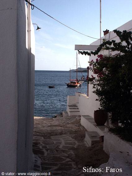 Whitewashed stone alley at Faros, Sifnos, with boats moored on the sea