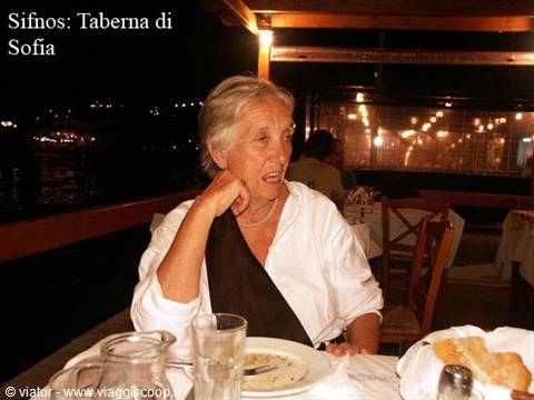 Woman dining at Sofia's taverna in Sifnos, warm night lights