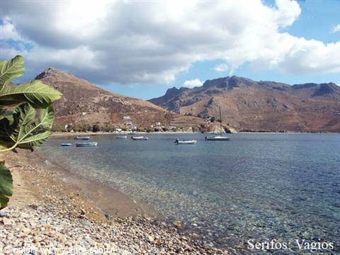 Pebble beach with anchored boats, arid hills and fig leaves at Vagios, Serifos