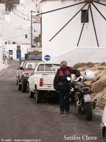 Man with motorcycle beside a white windmill in Serifos Chora