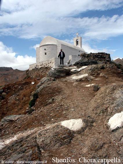 Man beside a whitewashed chapel with bell tower on Chora hill, Serifos