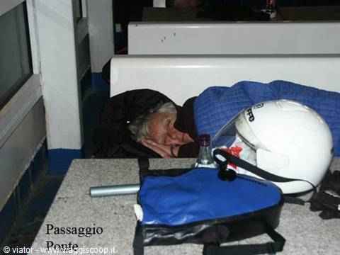 Passenger sleeping on ferry bench with helmet and blue bag