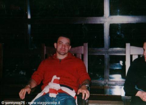 Man in red sweater sitting on wooden armchair indoors at night