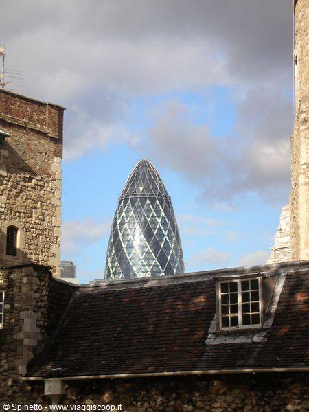 The Gherkin skyscraper seen between the ancient stone walls of the Tower of London