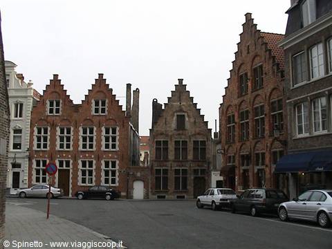 Red brick step-gabled houses on an empty square, car passing in Bruges