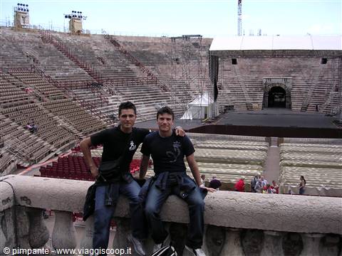 Two young men sitting on a stone balustrade inside Verona Arena