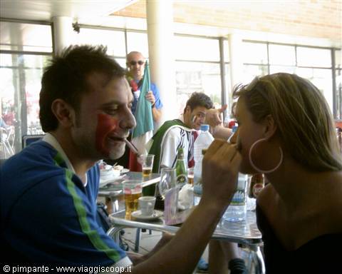 Painted football fans at a café table with beers and flags, playful moment