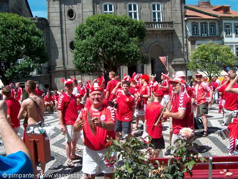 Danish fans in red cheer with drums before Guimarães' historic stone church