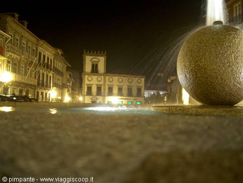 Night fountain with granite sphere beside illuminated historic buildings