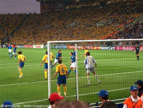 Football match at the stadium: blue goalkeeper, yellow-blue fans in the stands