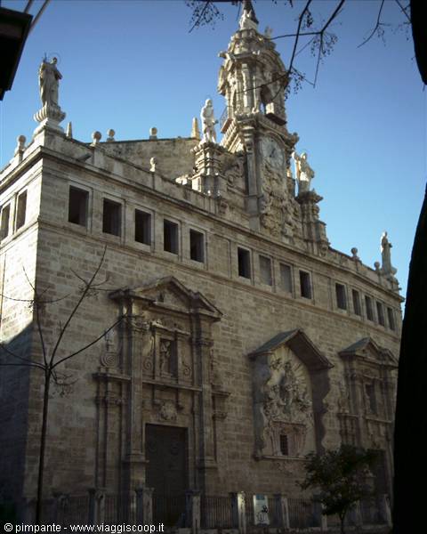 Baroque stone facade in Valencia, statues and clock tower under blue sky