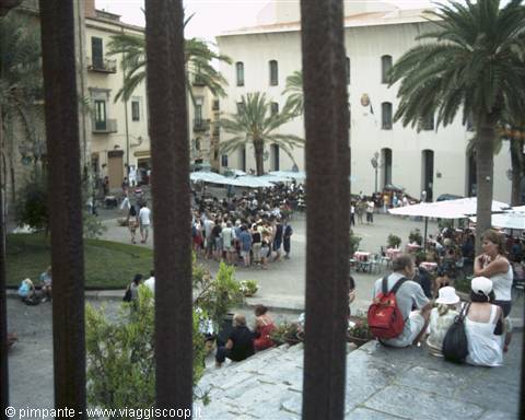 Tourists sitting on stone steps watching the crowded square below