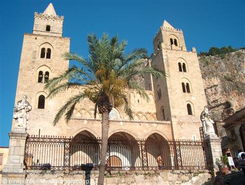 Cefalù Cathedral, stone facade with two Norman towers, palm tree and statues