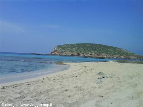 White sand beach with turquoise water, green rocky island in front