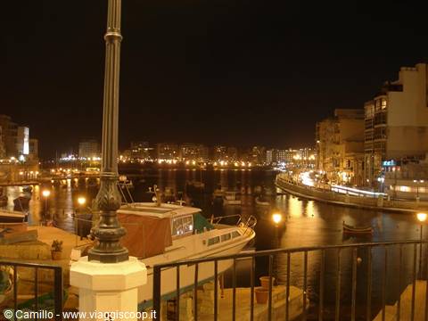 Boats moored at night in the lit harbour, iron lamp post in front