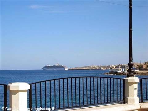 Cruise ship on the horizon behind a black iron railing by the sea