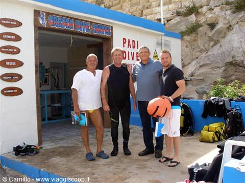 Four men in front of a Gozo dive center, one in wetsuit, diving gear nearby