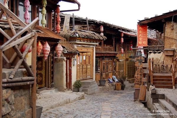 Cobbled alley lined with wooden houses and colorful lanterns, Dukezong