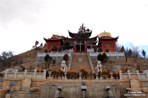 Stone stairs with guardian lions lead up to a red and golden temple