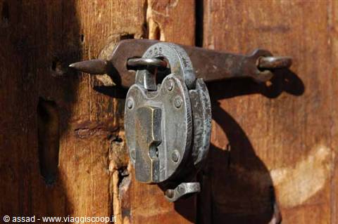 Old rusty padlock on a wooden door, direct sunlight