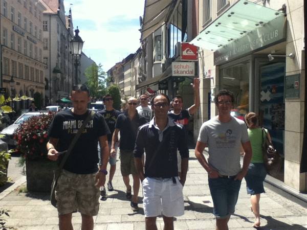 Group of tourists walking along a pedestrian street with shops and buildings