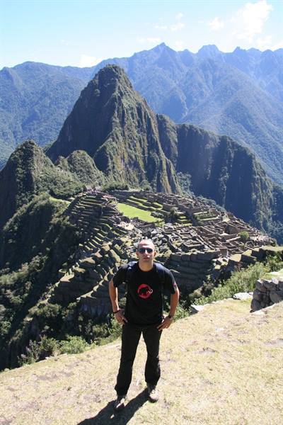 Tourist standing above the terraces and stone ruins of Machu Picchu