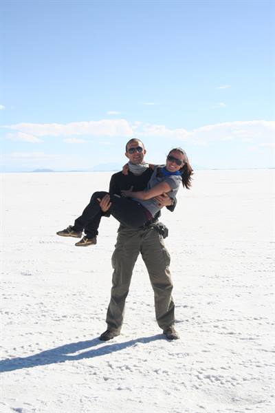Man carries laughing woman across the white salt of Salar de Uyuni